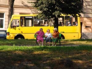 A group of elderly people sitting in frot of yellow bus